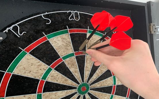 A dart board with three red darts being removed